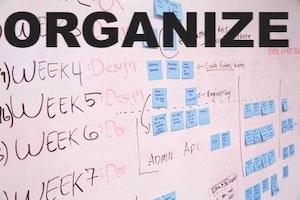whiteboard with post-its and notes and large black lettering reading 'organize'